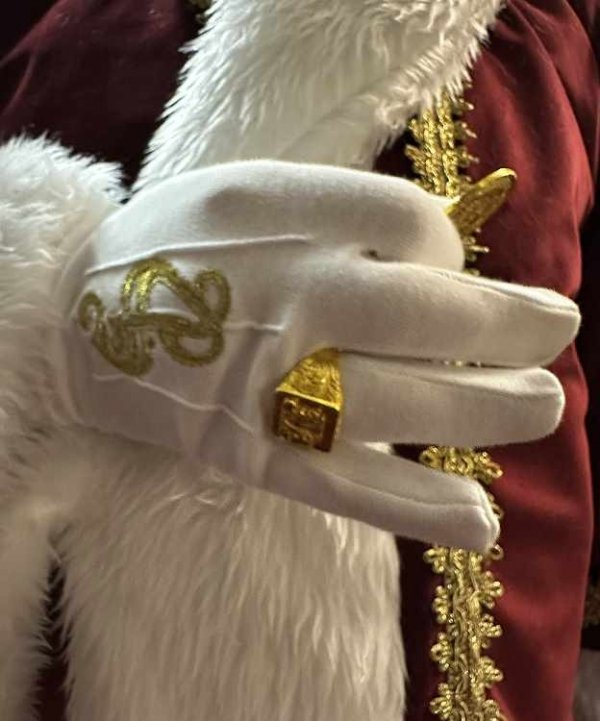 złoty sygnet Mikołaja na białej rękawicy – zbliżenie