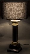 Złoto czarna lampa stojaca z czarnym abażurem.