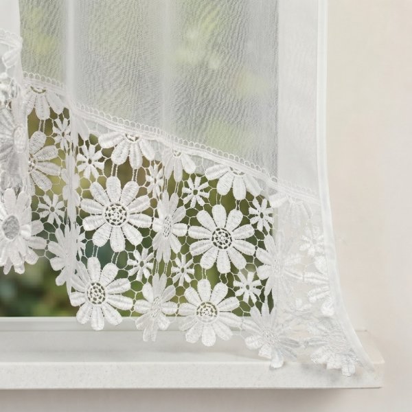 Zbliżenie na krawędź łuku firany Megan wykończoną dekoracyjną gipiurą.