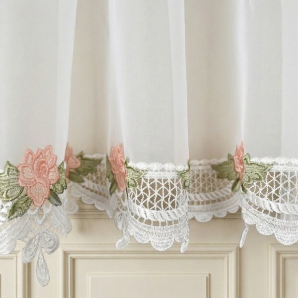 Zbliżenie na dolne wykończenie firany prezentujące szeroką gipiurę z motywem róż